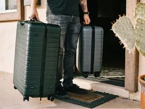 Man holding two hardside suitcases