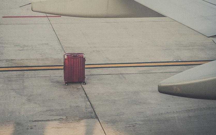 A single red aluminum suitcase left on the airstrip